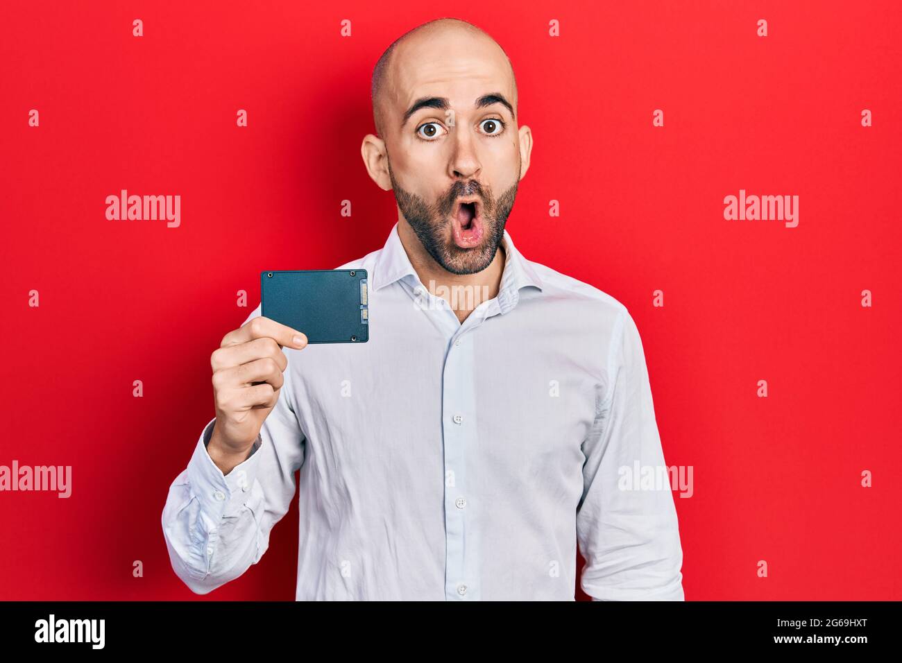 Young bald man holding ssd memory scared and amazed with open mouth for  surprise, disbelief face Stock Photo - Alamy