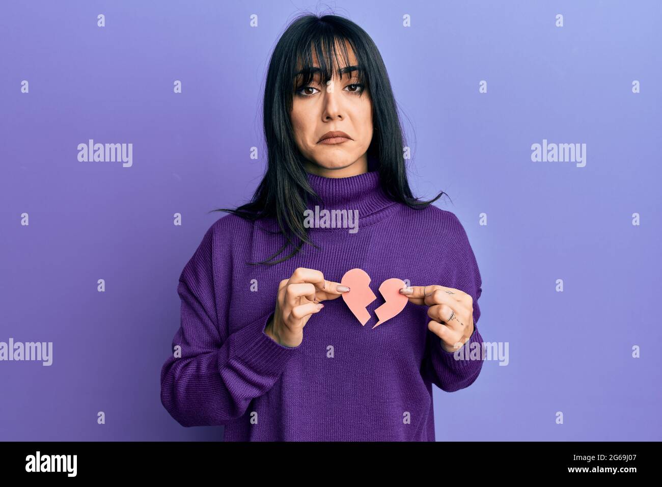 Young brunette woman with bangs holding broken heart paper shape ...