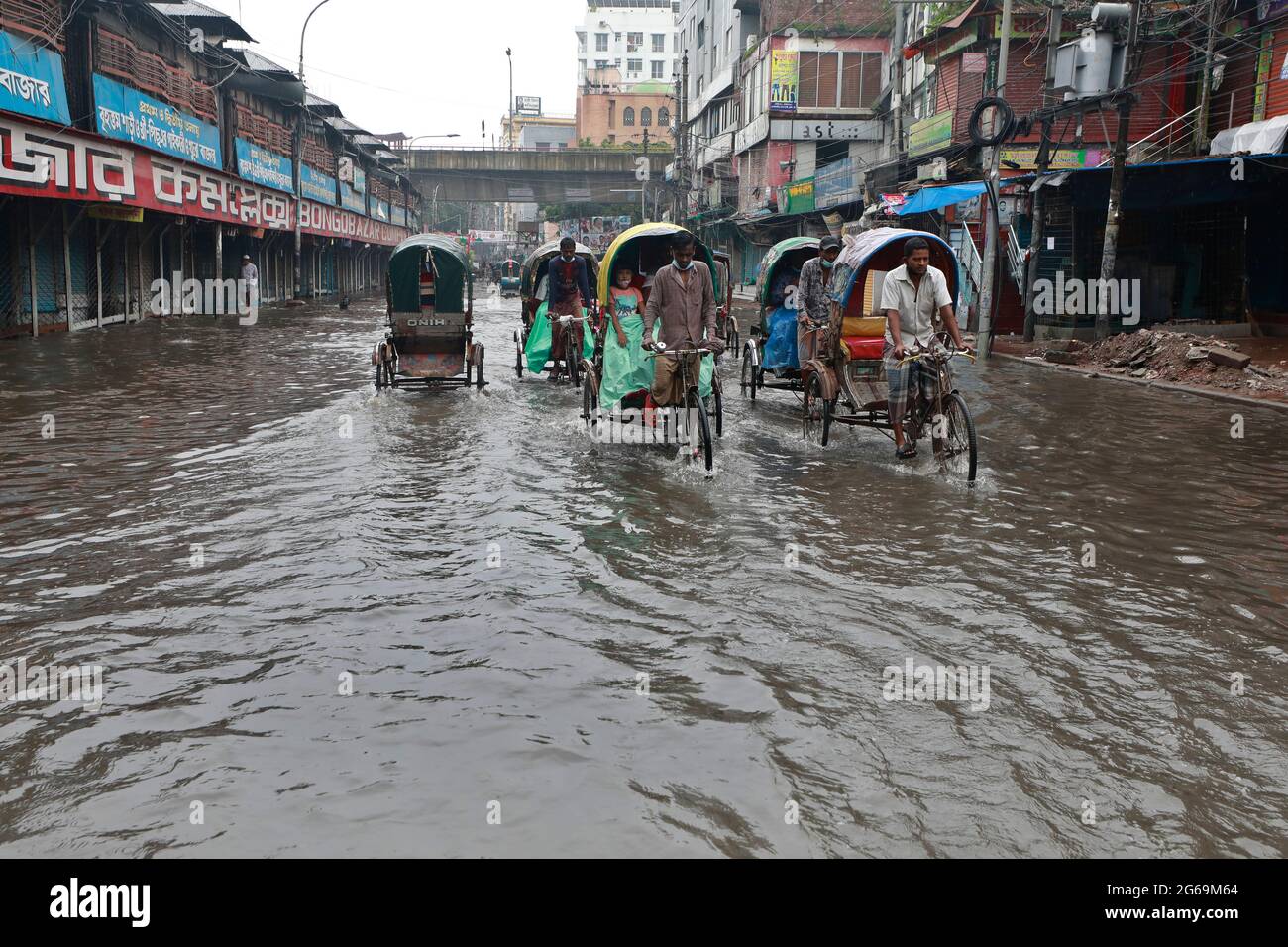 Dhaka, Bangladesh - July 04, 2021: Vehicles try to drive through a flooded street in Dhaka, Bangladesh. Encroachment of canals is contributing to the Stock Photo