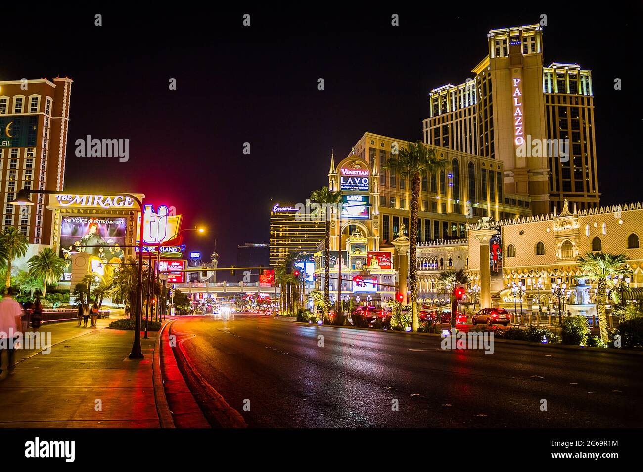 Palazzo and The Mirage on the Strip in Las Vegas at night with people walking on the street Stock Photo