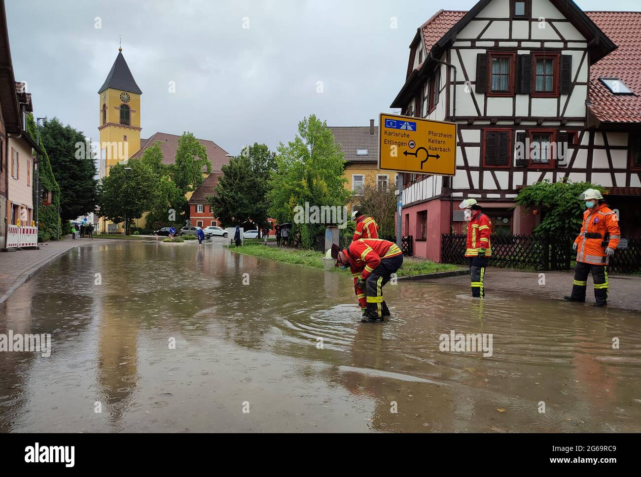 Karlsbad, Germany. 04th July, 2021. Firefighters stand on a flooded street after a storm. (to 'Thunderstorm expected in Baden-Württemberg - flooding in Karlsbad') Credit: Thomas Riedel/dpa/Alamy Live News Stock Photo