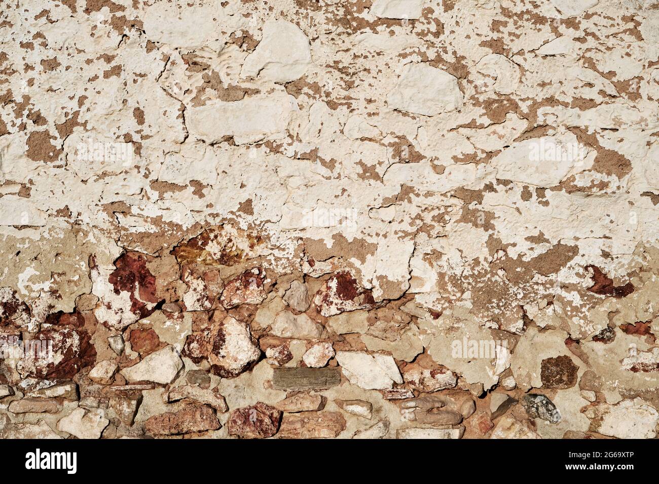 Old traditional limewashed stone wall with peeling plaster, white rustic background or texture Stock Photo