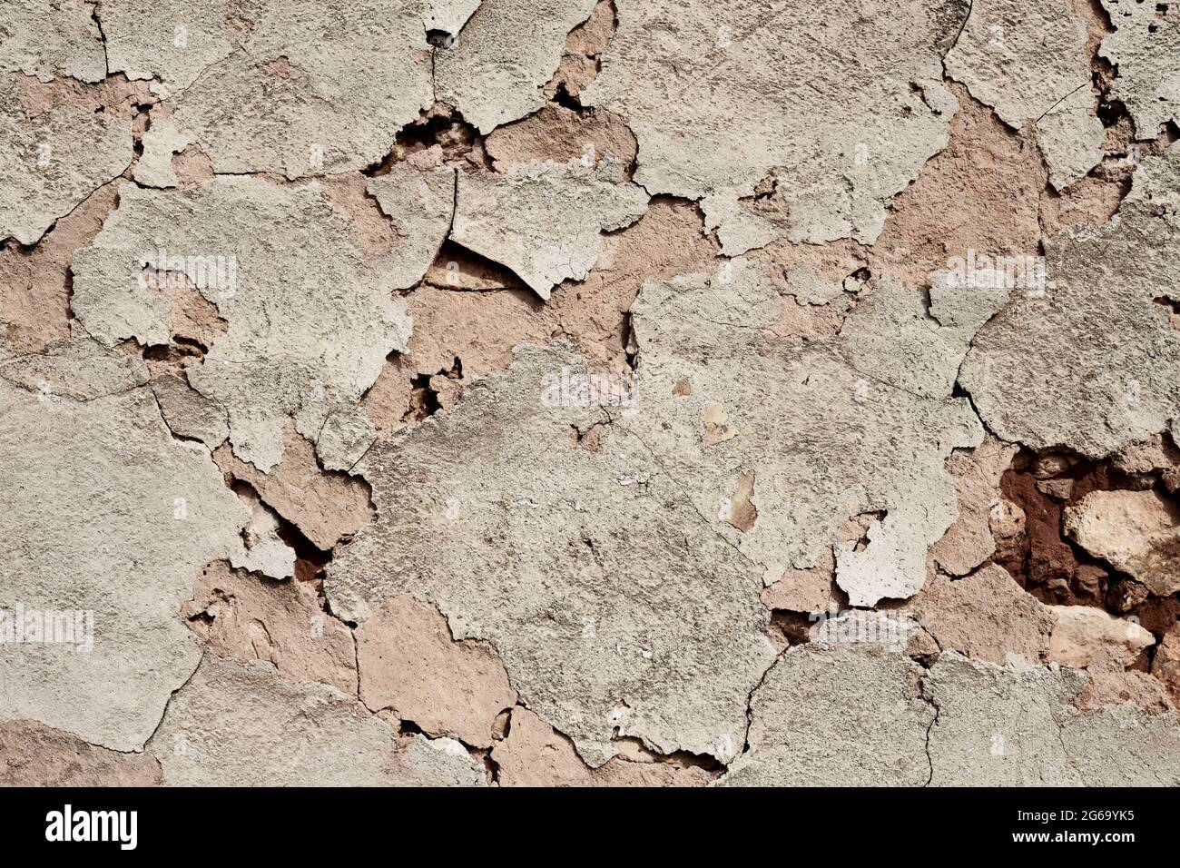 Old traditional limewashed stone wall with peeling plaster, white rustic background Stock Photo