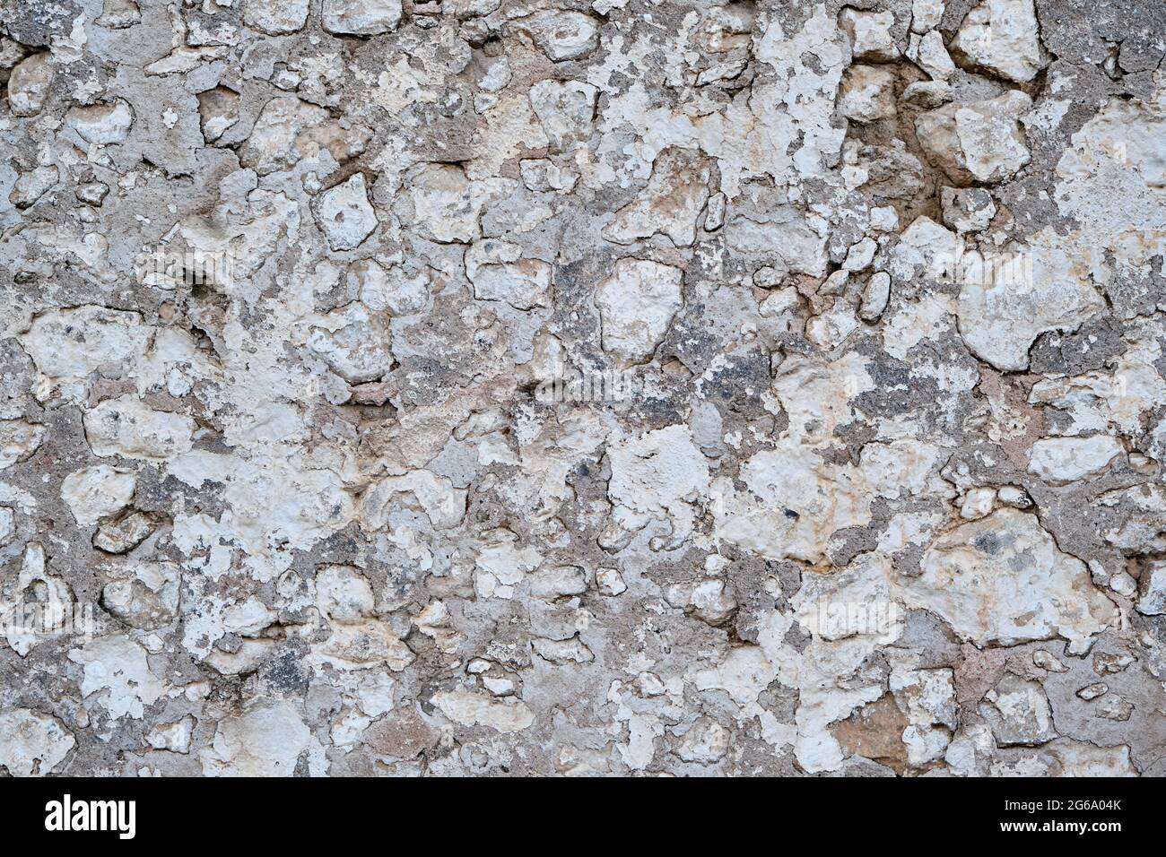 Old traditional limewashed stone wall with peeling plaster, white rustic background or texture Stock Photo