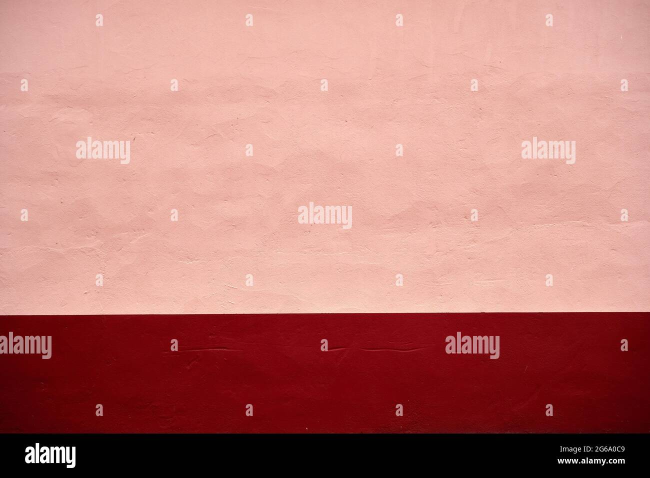 Pink pastel painted concrete wall with dark red red baseboard, abstract ...