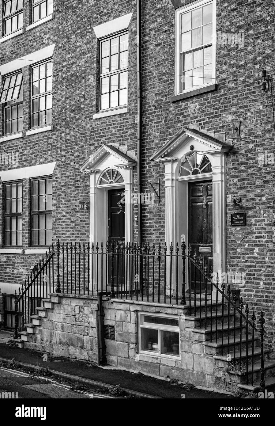 Two ornate doorways raised from ground level and accessible by steps.  Railings line the steps and an evening sun catches the brickwork. Stock Photo