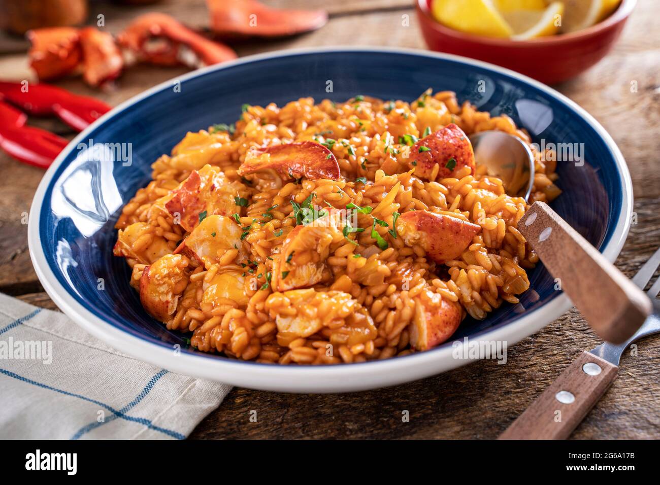 A bowl of delicious lobster saffron risotto on a rustic wood table top. Stock Photo