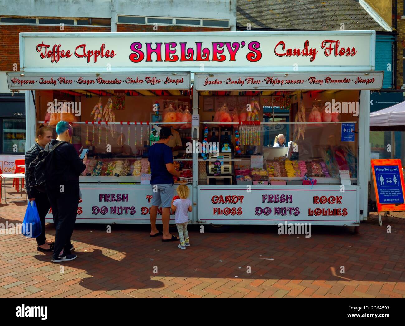 Shoppers and children enjoying refreshment at Shelley's candy floss and toffee apple food stall in the weekly Market  Redcar High Street Cleveland Eng Stock Photo