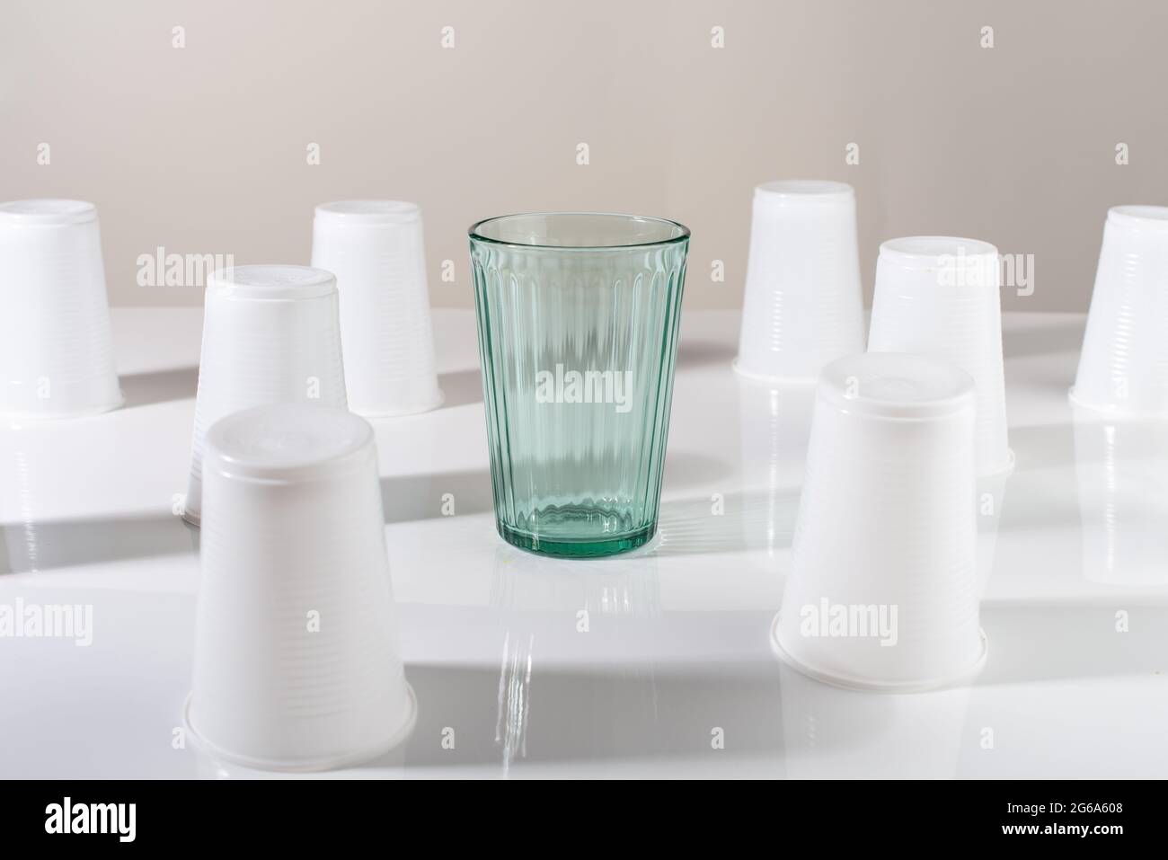 Glass among many plastic cups. Glass or plastic. Reusable versus