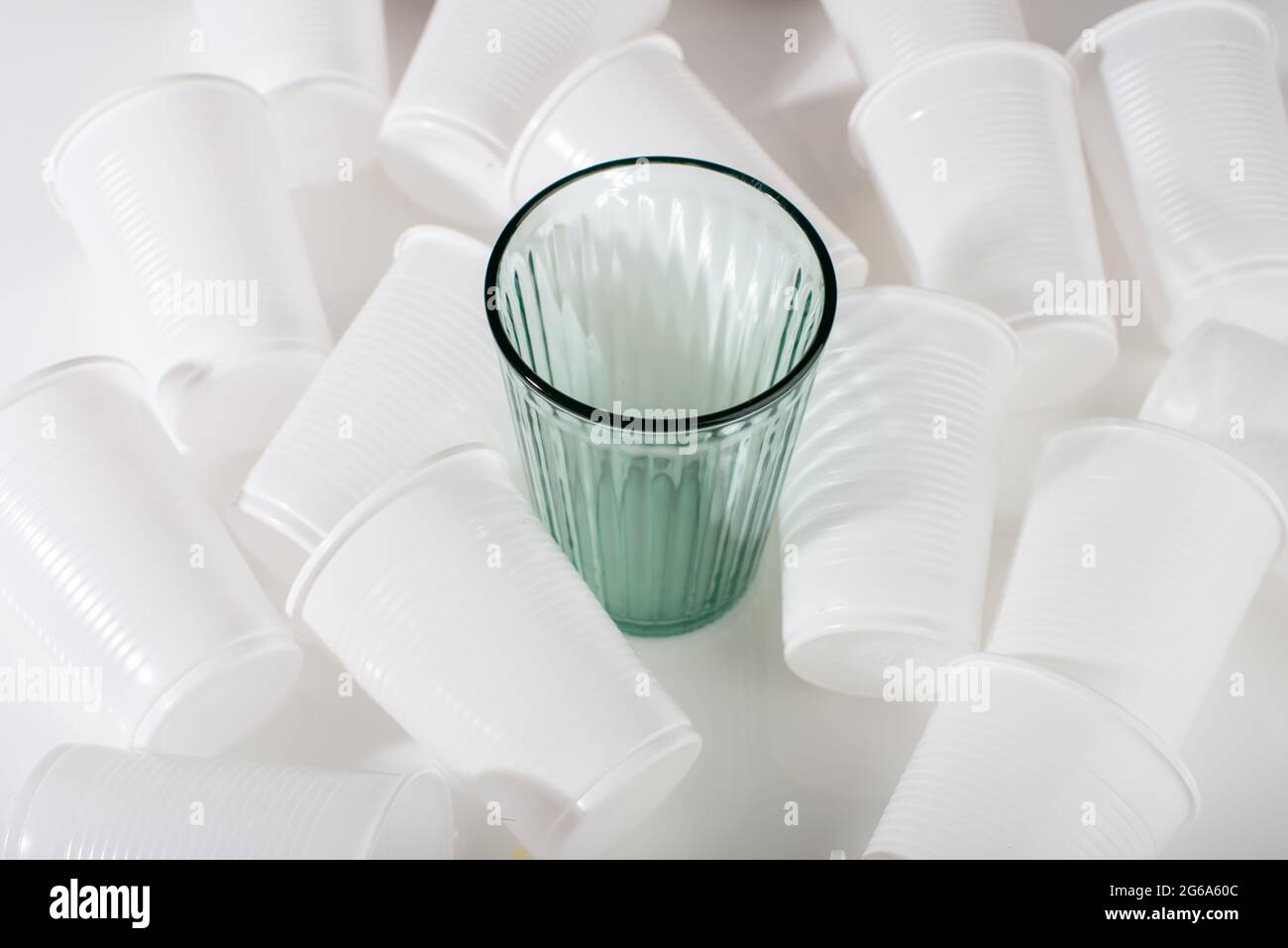 Glass among many plastic cups. Glass or plastic. Reusable versus