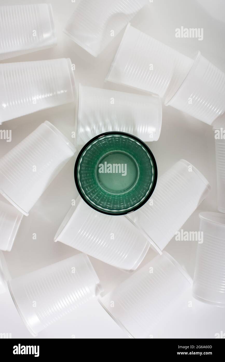 Glass among many plastic cups. Glass or plastic. Reusable versus
