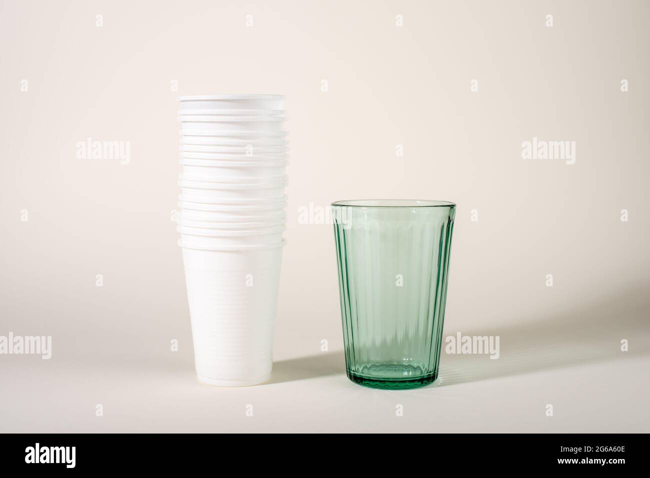 Glass and stack of plastic cups. Glass or plastic. Reusable versus