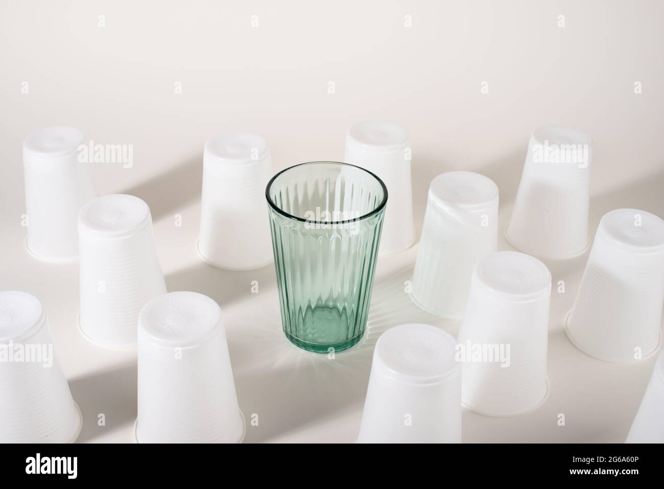Glass among many plastic cups. Glass or plastic. Reusable versus