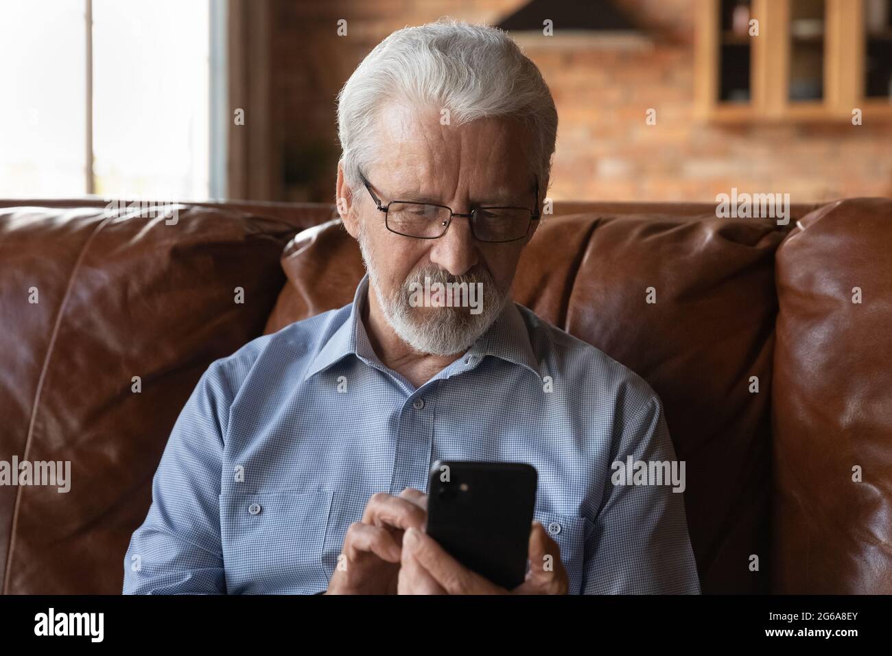 Focused elder 70s man using telemedicine app on smartphone Stock Photo