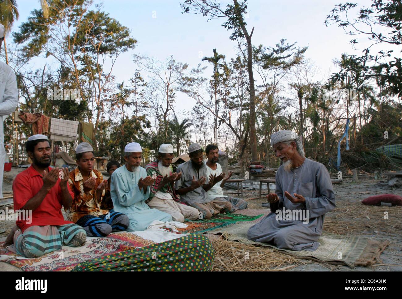 Muslims saying their prayers in front of a ruined mosque in Kakchira, Borguna, Bangladesh. Many houses were destroyed by tidal wave on the night of 15th November as cyclone SIDR smashes the coastal areas causing huge damage to lives and properties. In Kakchira, 300 people died and 300 more are missing by the massive hit of the cyclone. November 23, 2007. Stock Photo