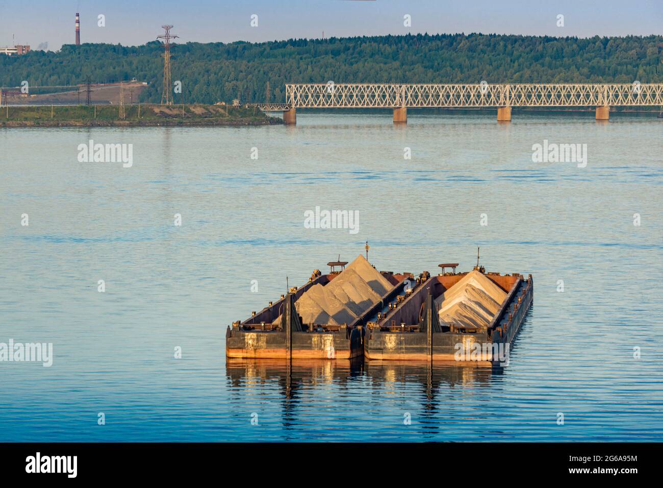 dry cargo barges with sand for construction stand on the roadstead against the background of bridges across the river Stock Photo