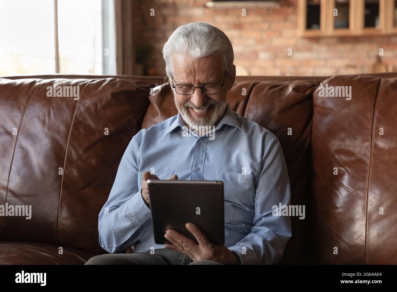 Happy elderly retired 70s man using online app on tablet Stock Photo