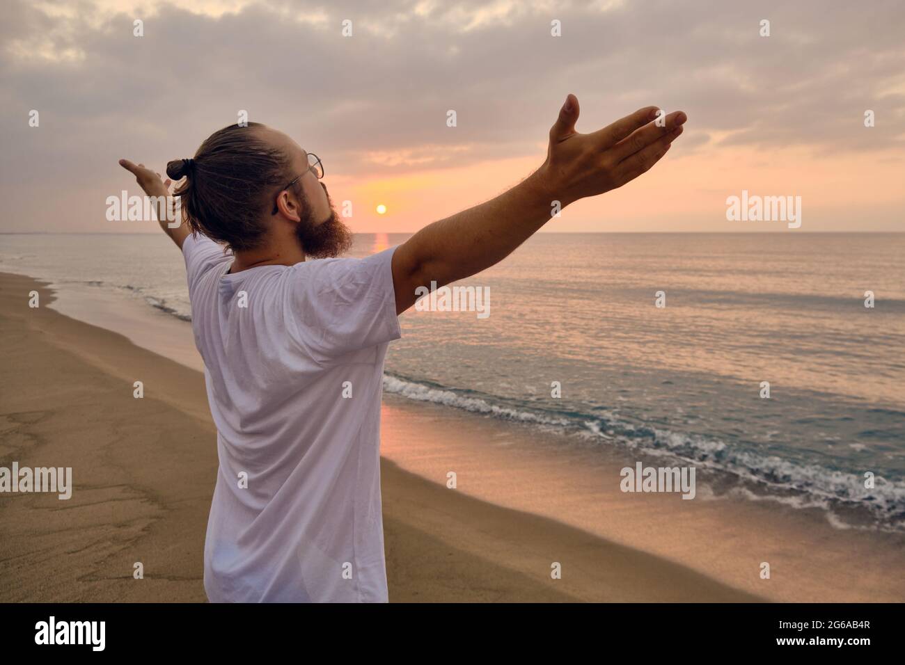 man practices surya namaskar pose at sea beach 2G6AB4R