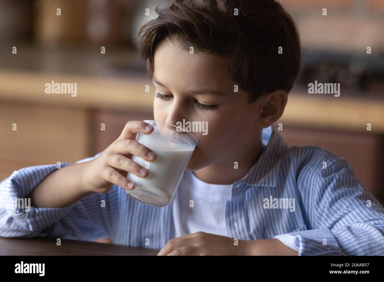 Preschooler boy drinking milk from glass during breakfast in kitchen Stock Photo