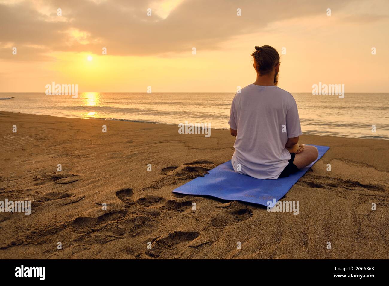 Man sits in lotus position at beach Stock Photo