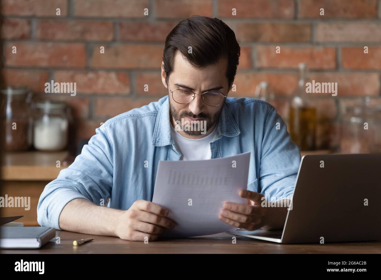 Serious distance employee analyzing statistics, data in paper financial reports Stock Photo