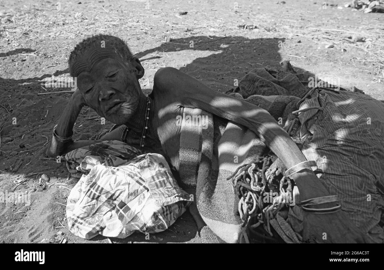 Botswana: A old bushmen woman lying on the sand in the shadow of the central Kalahari ready to die soon Stock Photo