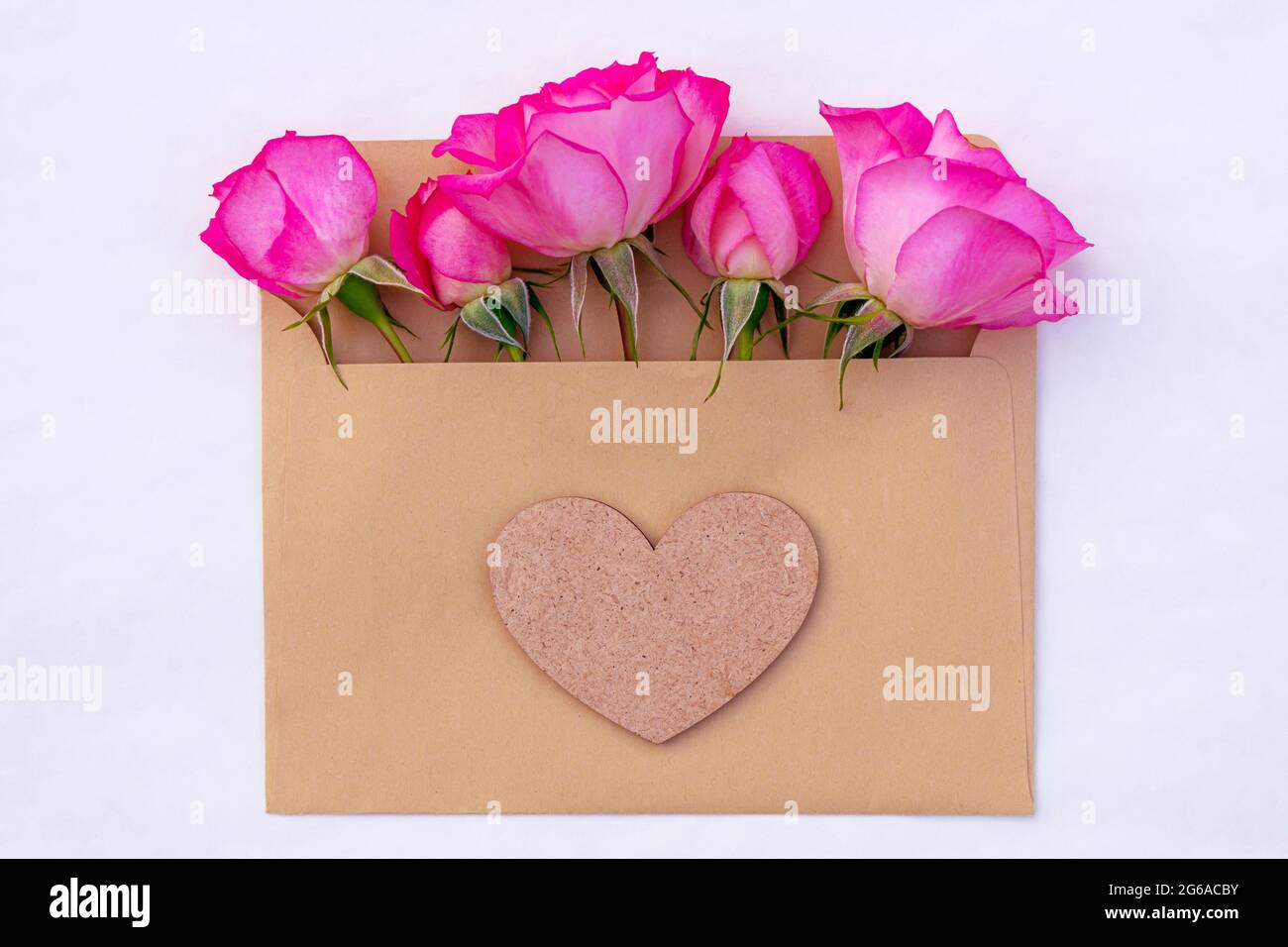 Pink roses in an envelope with a heart isolated on white background Stock Photo