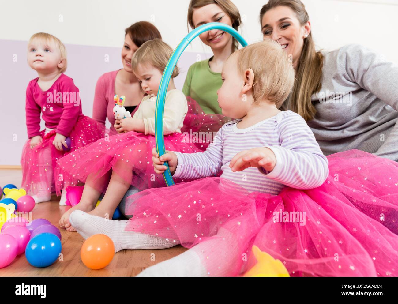 Toddler in pink dress playing with hula hoop Stock Photo
