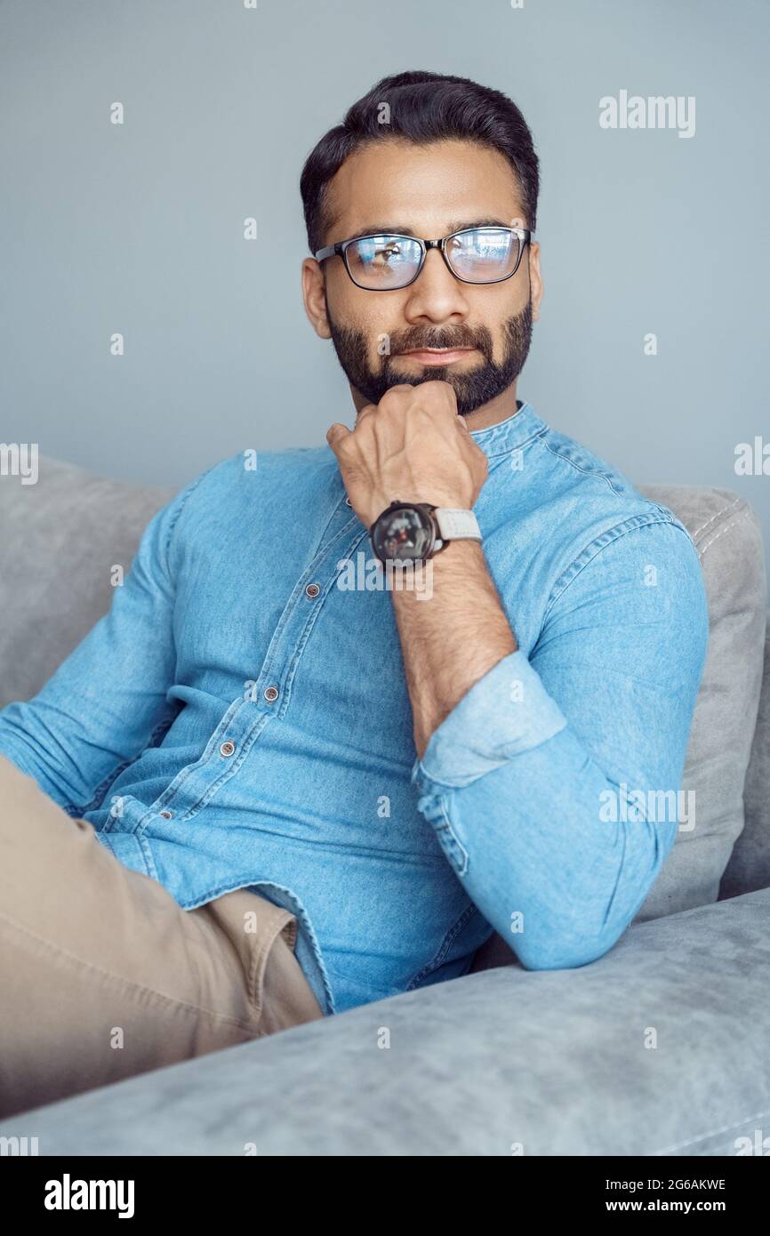 Pensive indian business man executive thinking sitting on sofa looking aside Stock Photo
