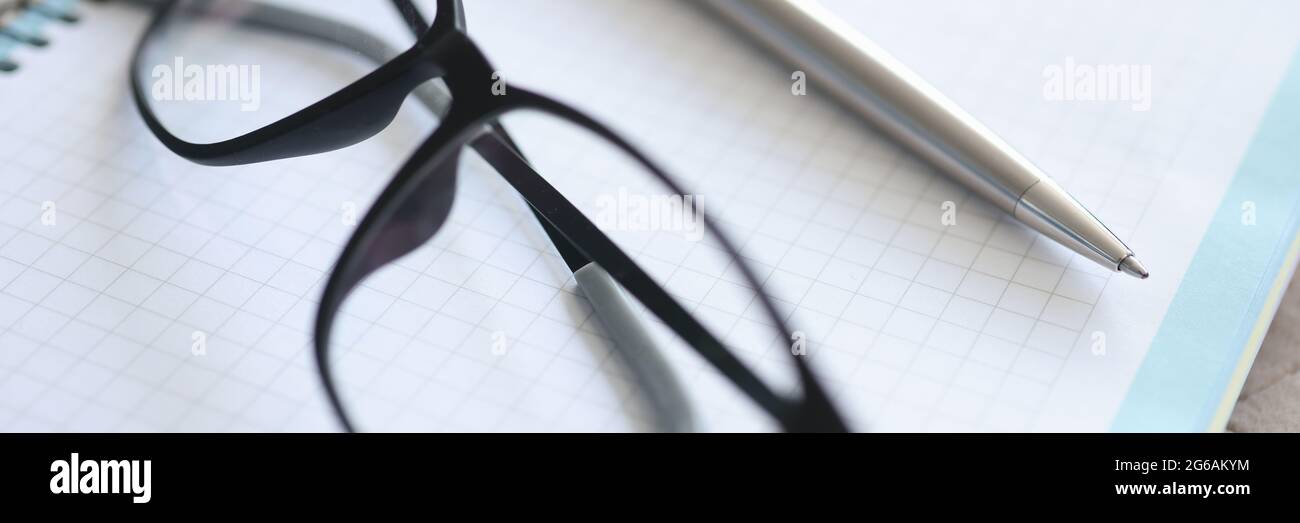 Black-framed glasses, pen, notebook lie on table Stock Photo