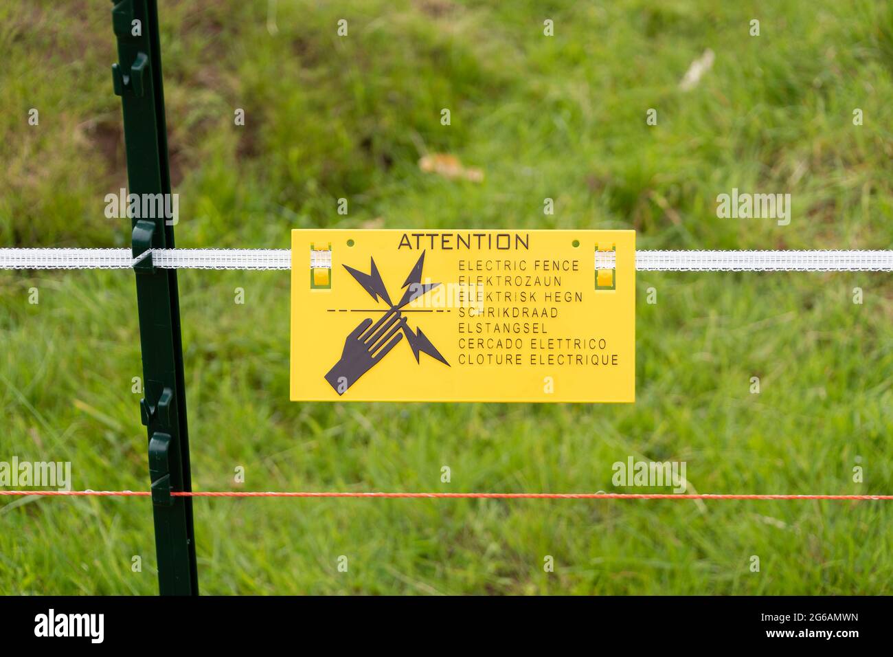 An electric fence warning sign in multiple languages Stock Photo