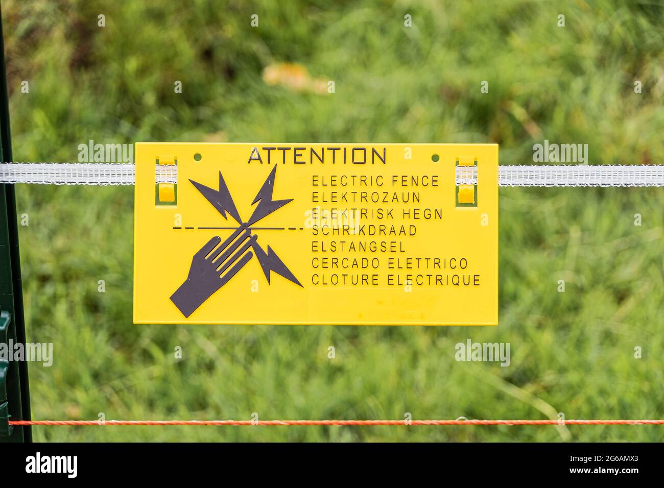 An electric fence warning sign in multiple languages Stock Photo