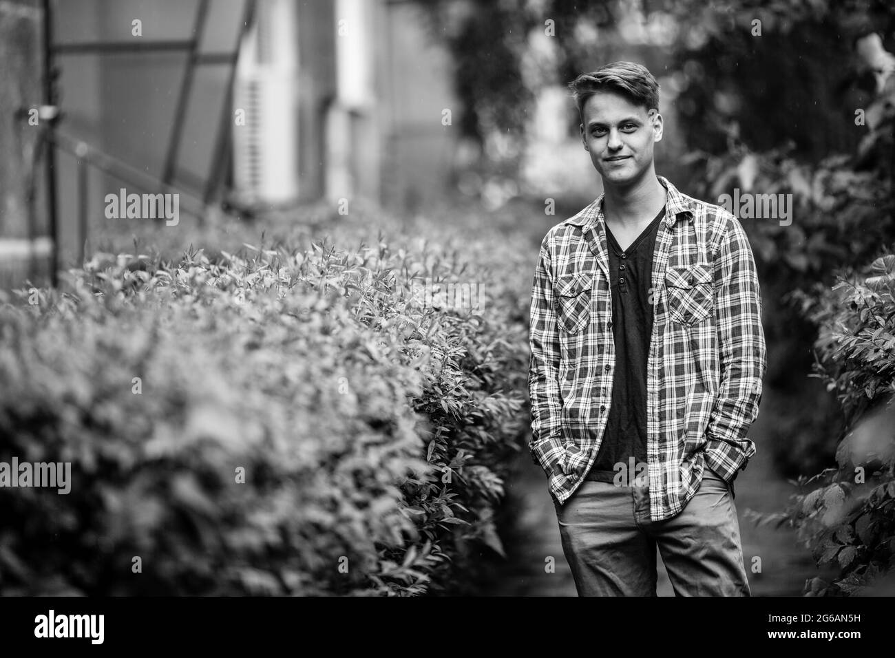 A young man is standing in the outdoors. Black and white photo. Stock Photo