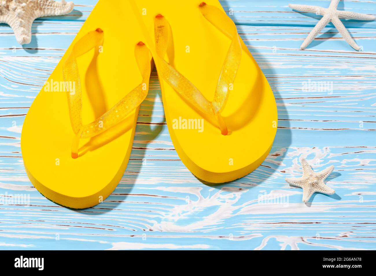 yellow rubber beach flip flops and starfish on a blue wooden background ...