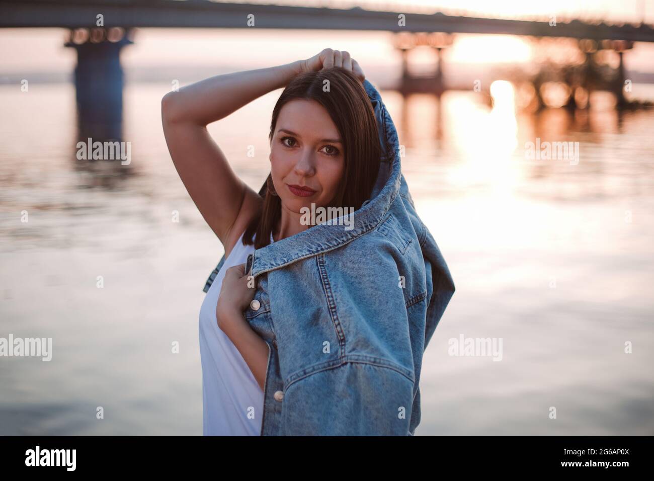 Gorgeous brunette girl with long flowing hair dressed in jeans jacket and jeans  poses standing on the dark background in the studio Stock Photo by  Leikaproduction 247804188