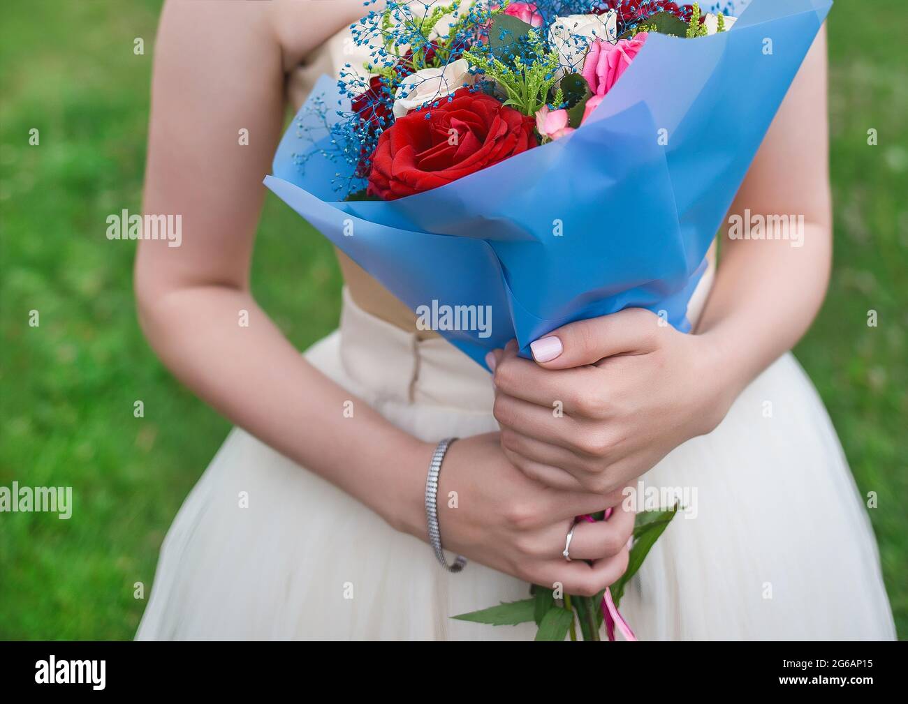 The bride's hands in the wedding dress hold a bouquet of colorful ...