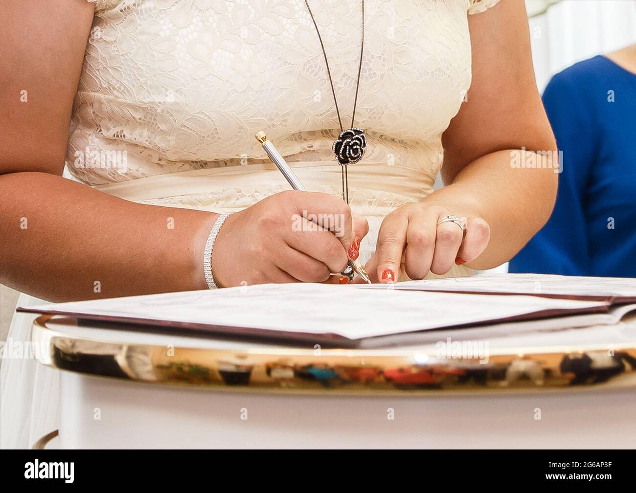 The girl's hands at the wedding put their signature pen in the magazine about marriage registration. Stock Photo