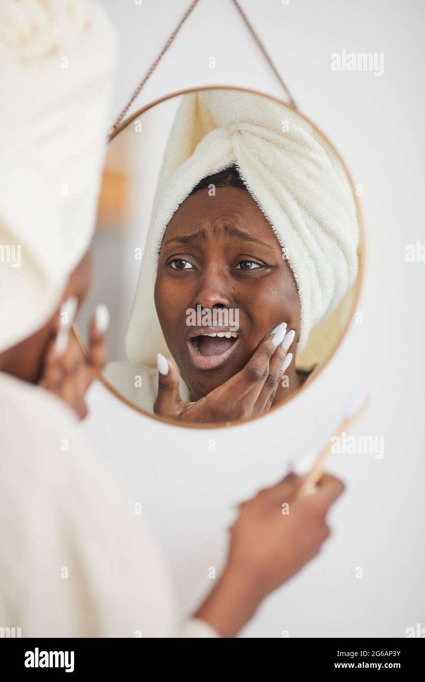 Vertical portrait of young African-American woman suffering from toothache and gum pain while brushing teeth in morning, copy space Stock Photo