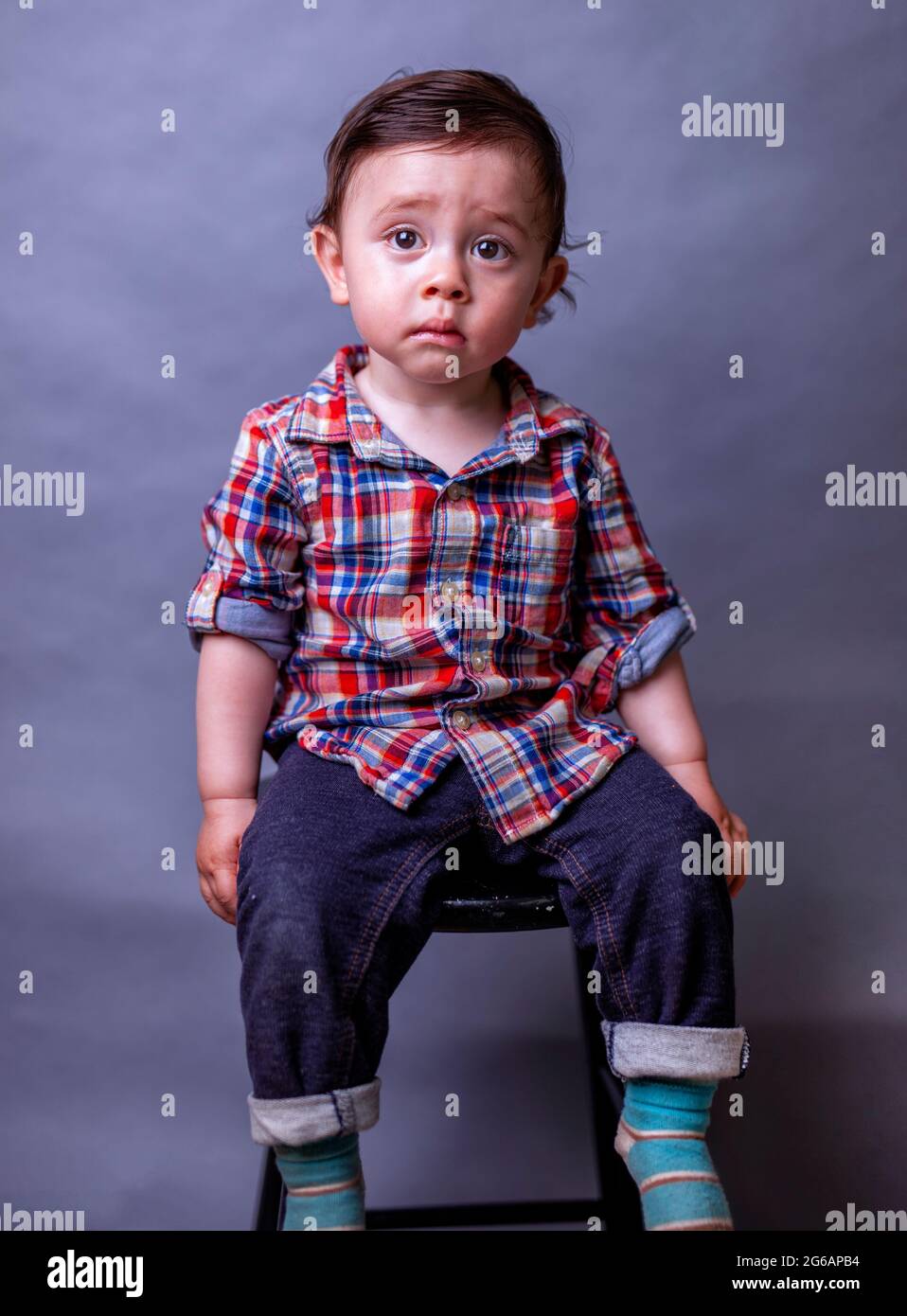 portrait of cute but serious toddler boy wearing plaid shirt and blue jeans Stock Photo