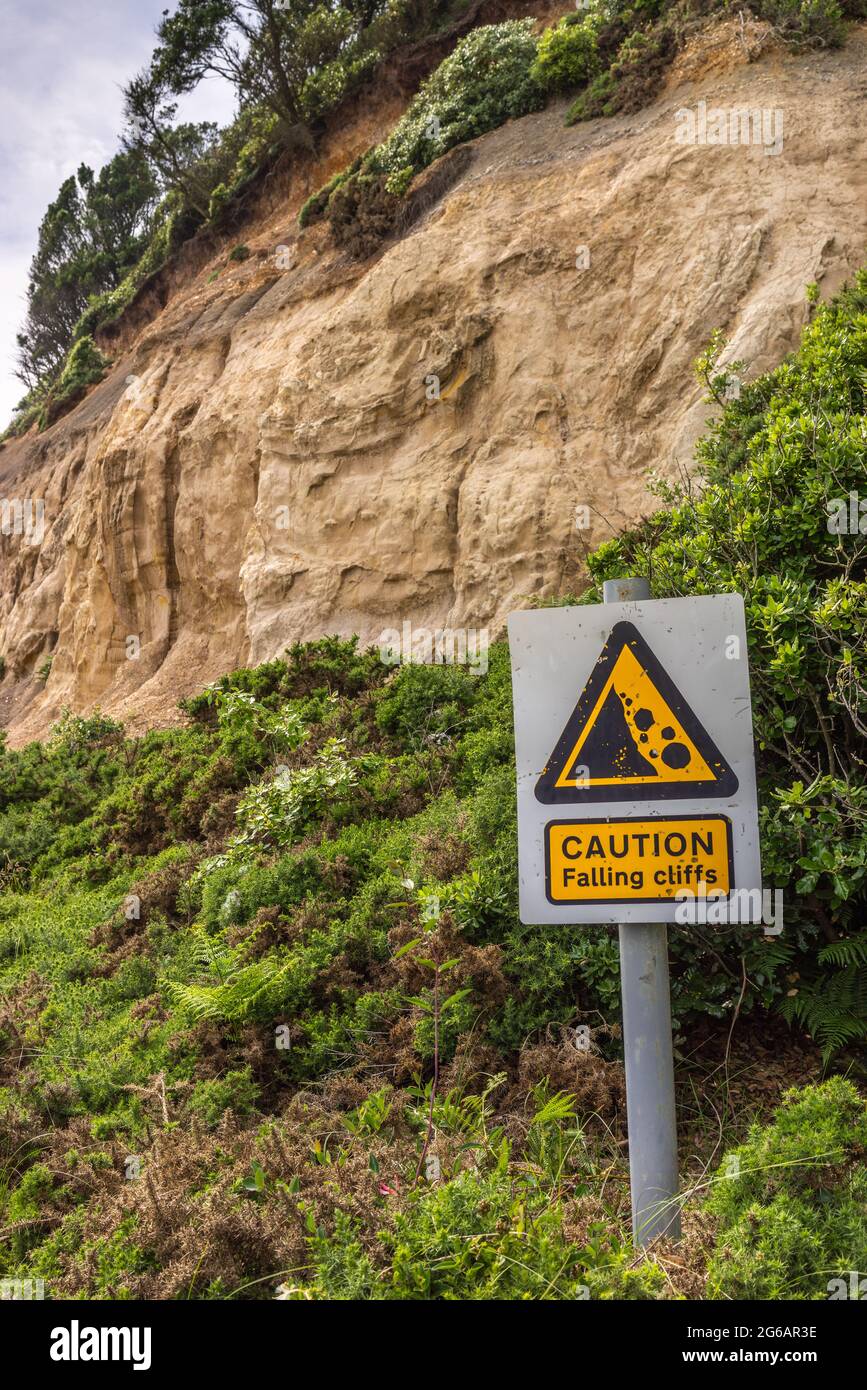 'Caution - Falling cliffs' sign due to coastal erosion along the Southern coast at Highcliffe Beach, Dorset, England, UK Stock Photo