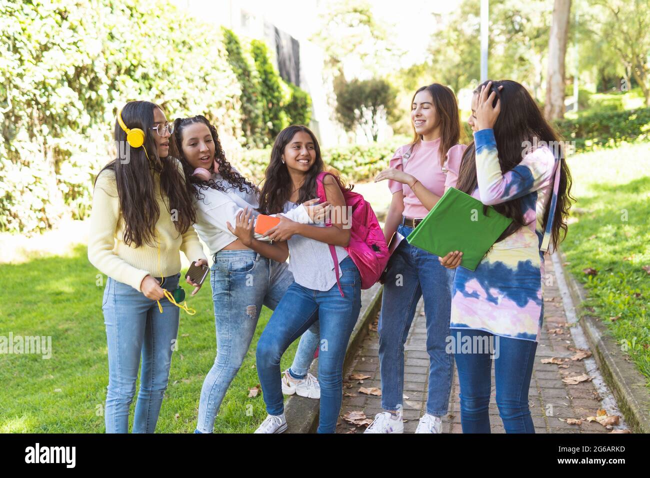 Group of five Latina teenage students laughing happily on the way to high school Stock Photo