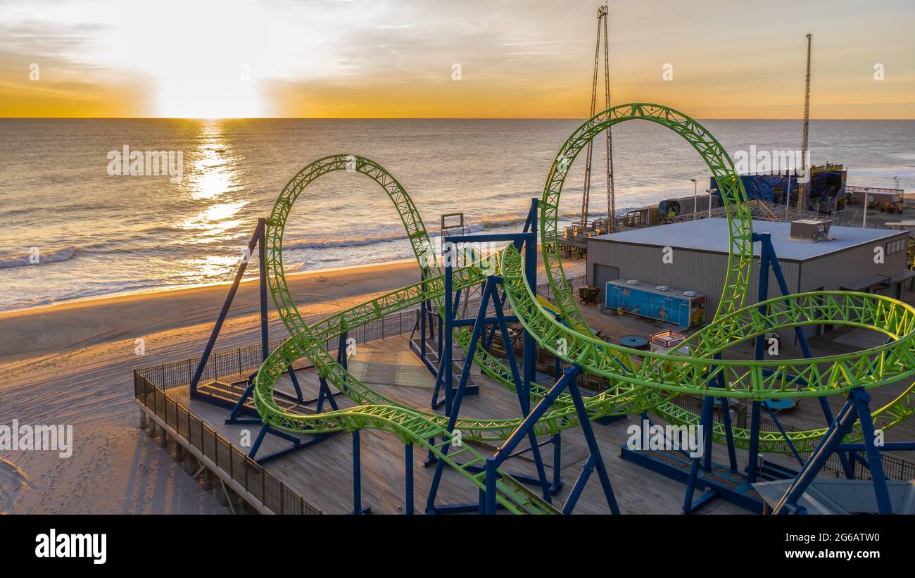 Aerial of a green roller coaster at sunrise on the beach. Stock Photo