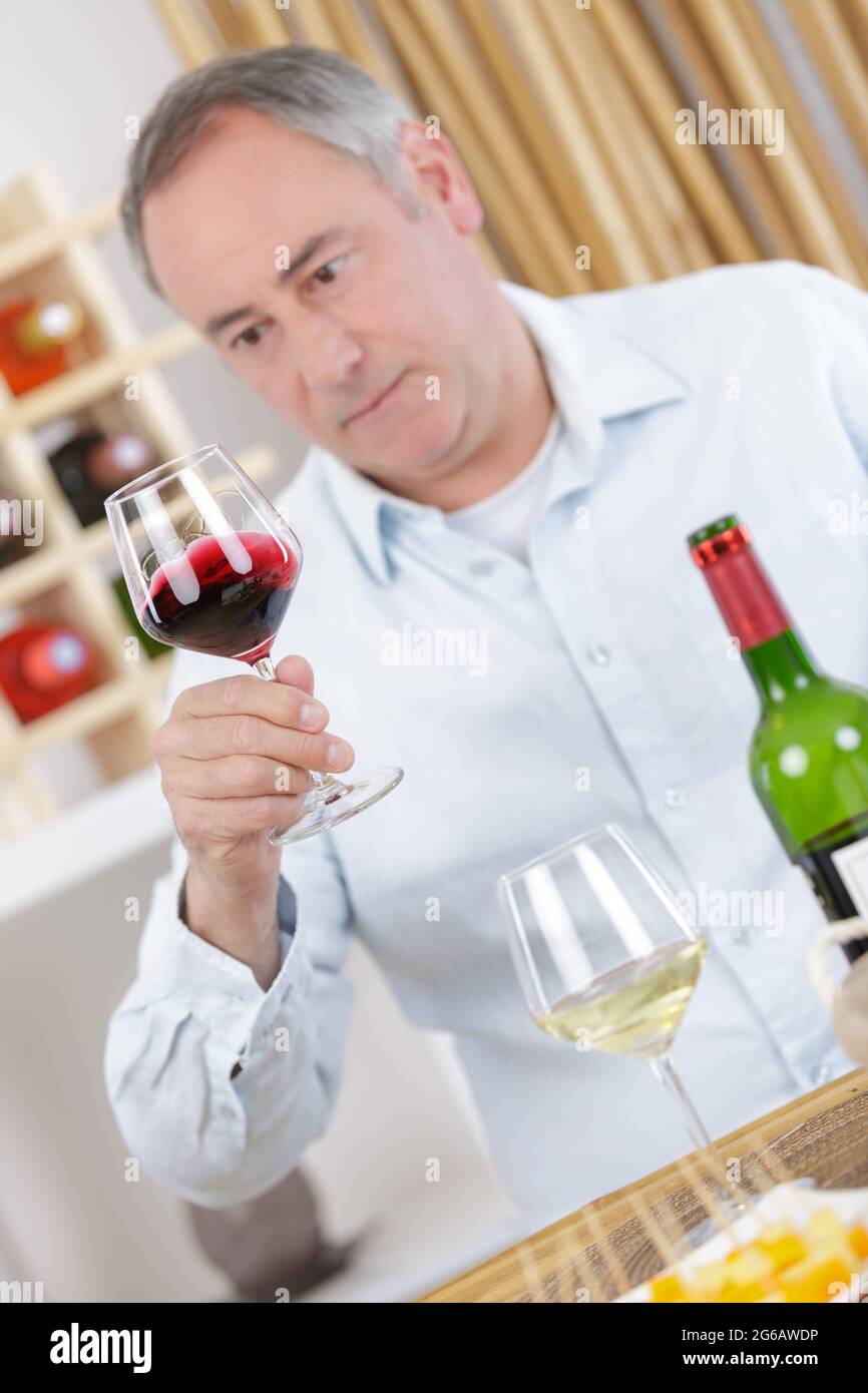 elderly man looking at a red wine in the glass Stock Photo - Alamy
