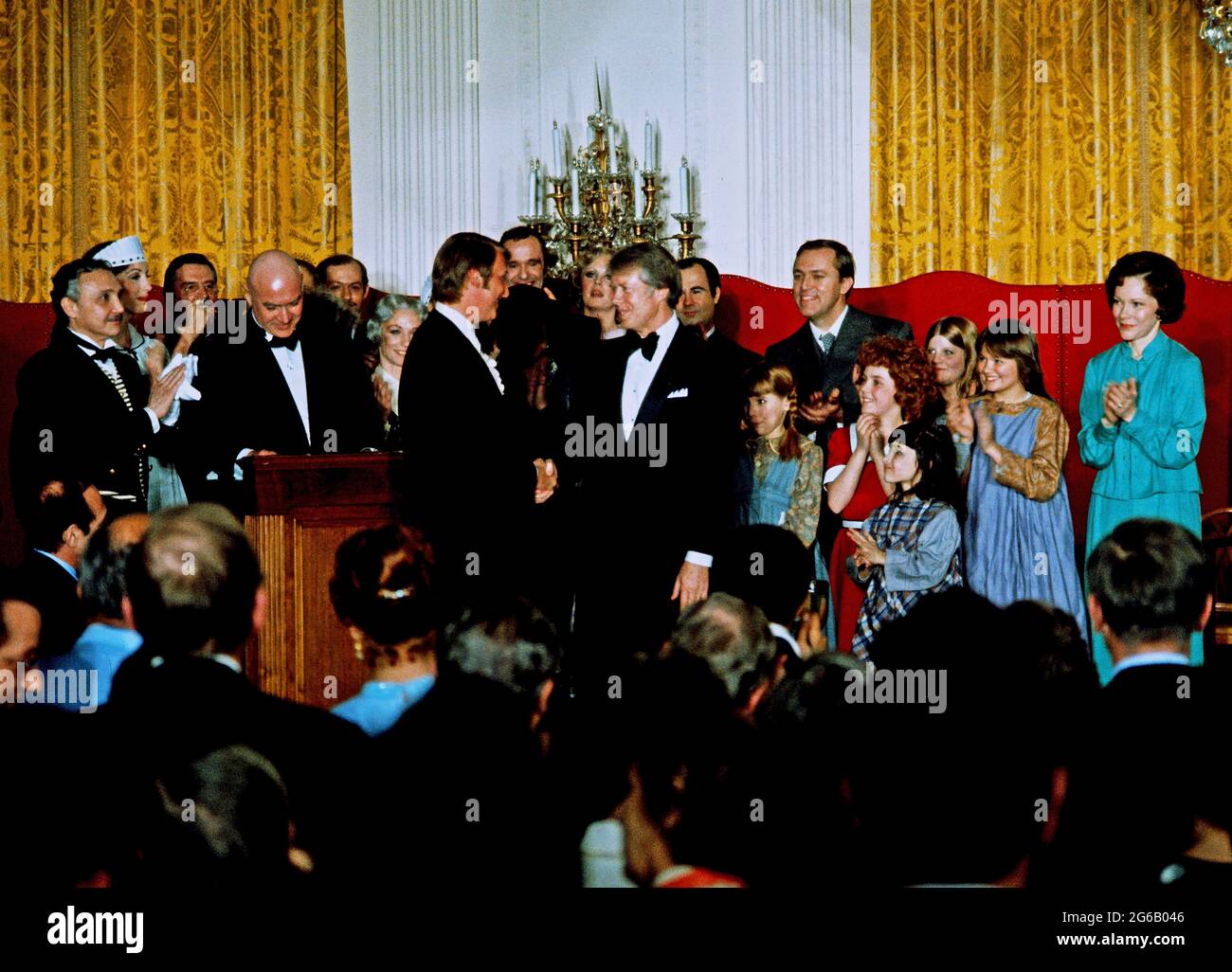 United States President Jimmy Carter shakes hands with director Mike Nichols as he and first lady Rosalynn Carter, right, pose with the cast of “Annie” as they host a dinner in honor of the State Governors and their spouses in the East Room of the White House in Washington, DC on Tuesday, March 1, 1977. (Photo by Arnie Sachs/CNP/Sipa USA) Credit: Sipa USA/Alamy Live News Stock Photo