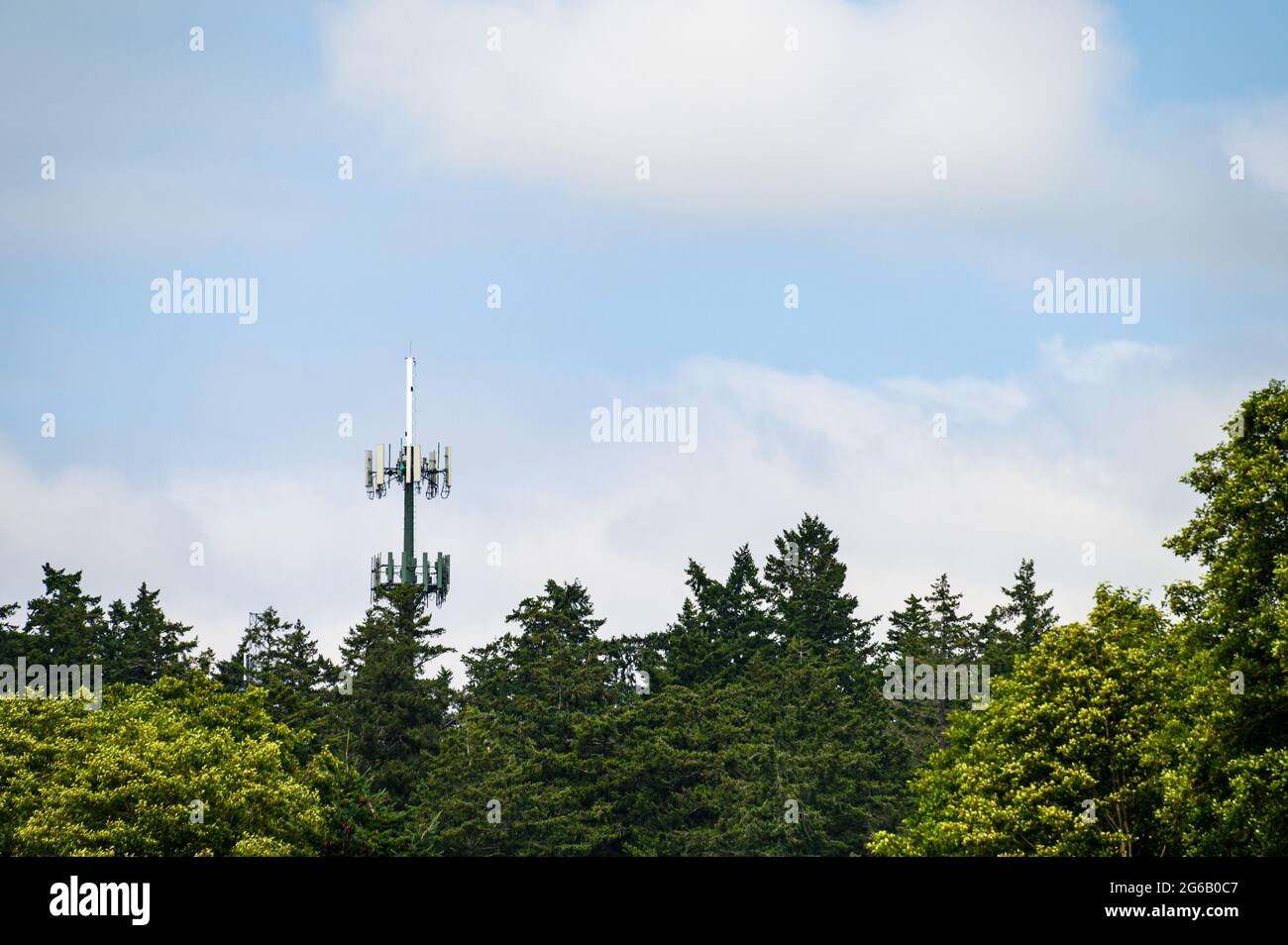 Mobile communications tower with antennas on top, showing above a ...