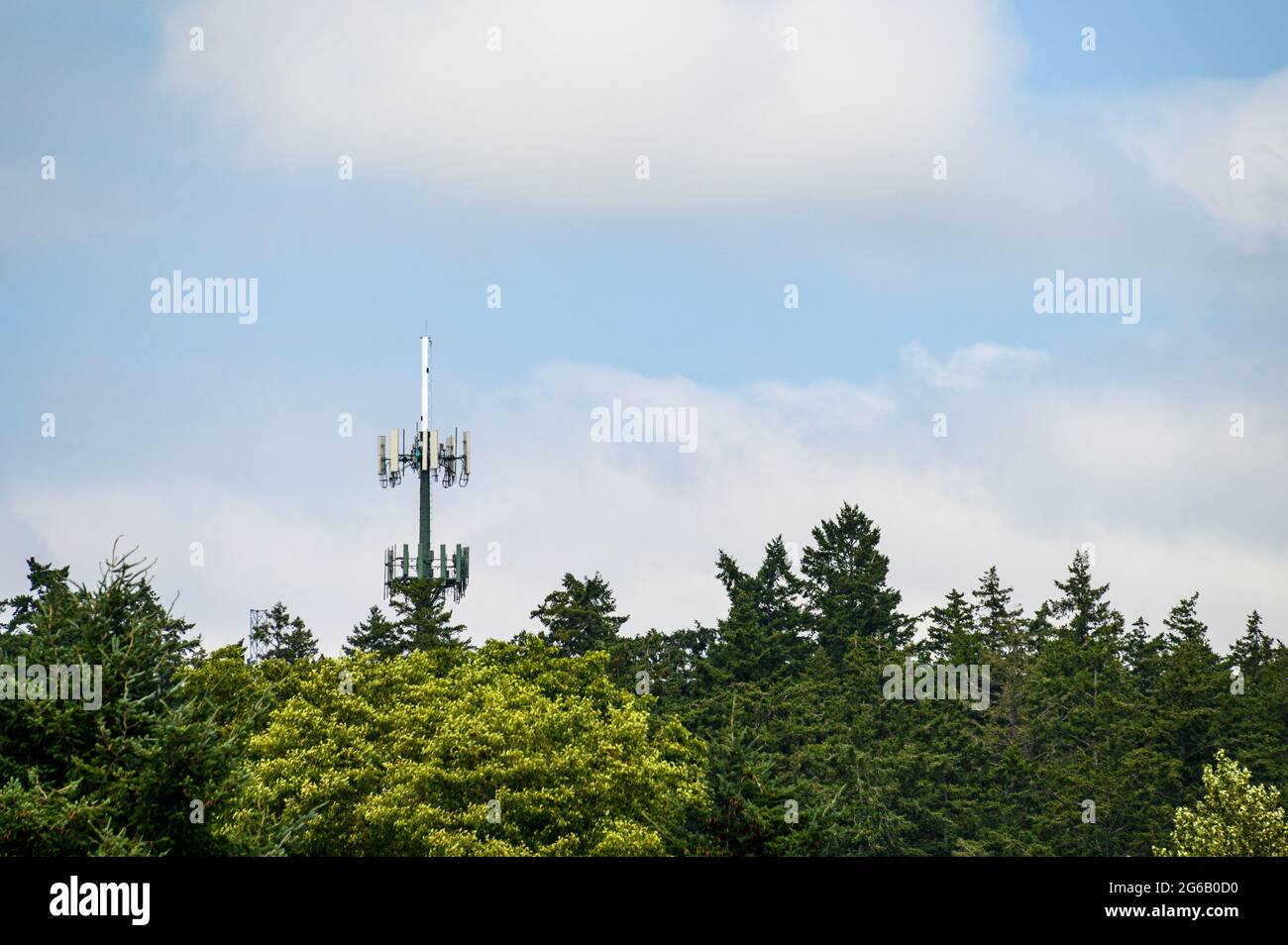 Mobile communications tower with antennas on top, showing above a ...