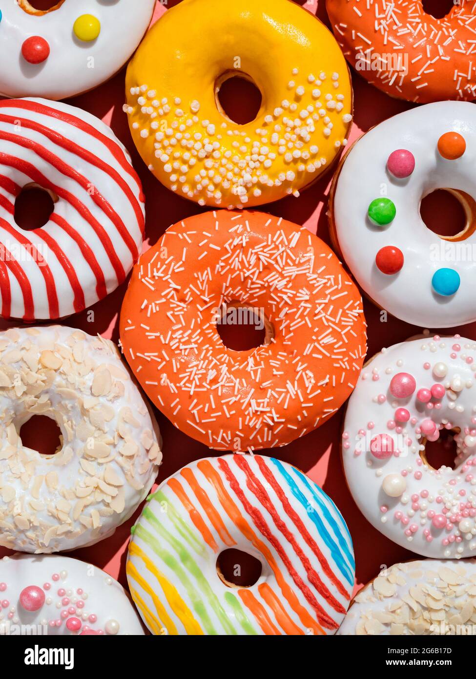 Assorted colorful glazed donuts with sprinkle. Creative layout made