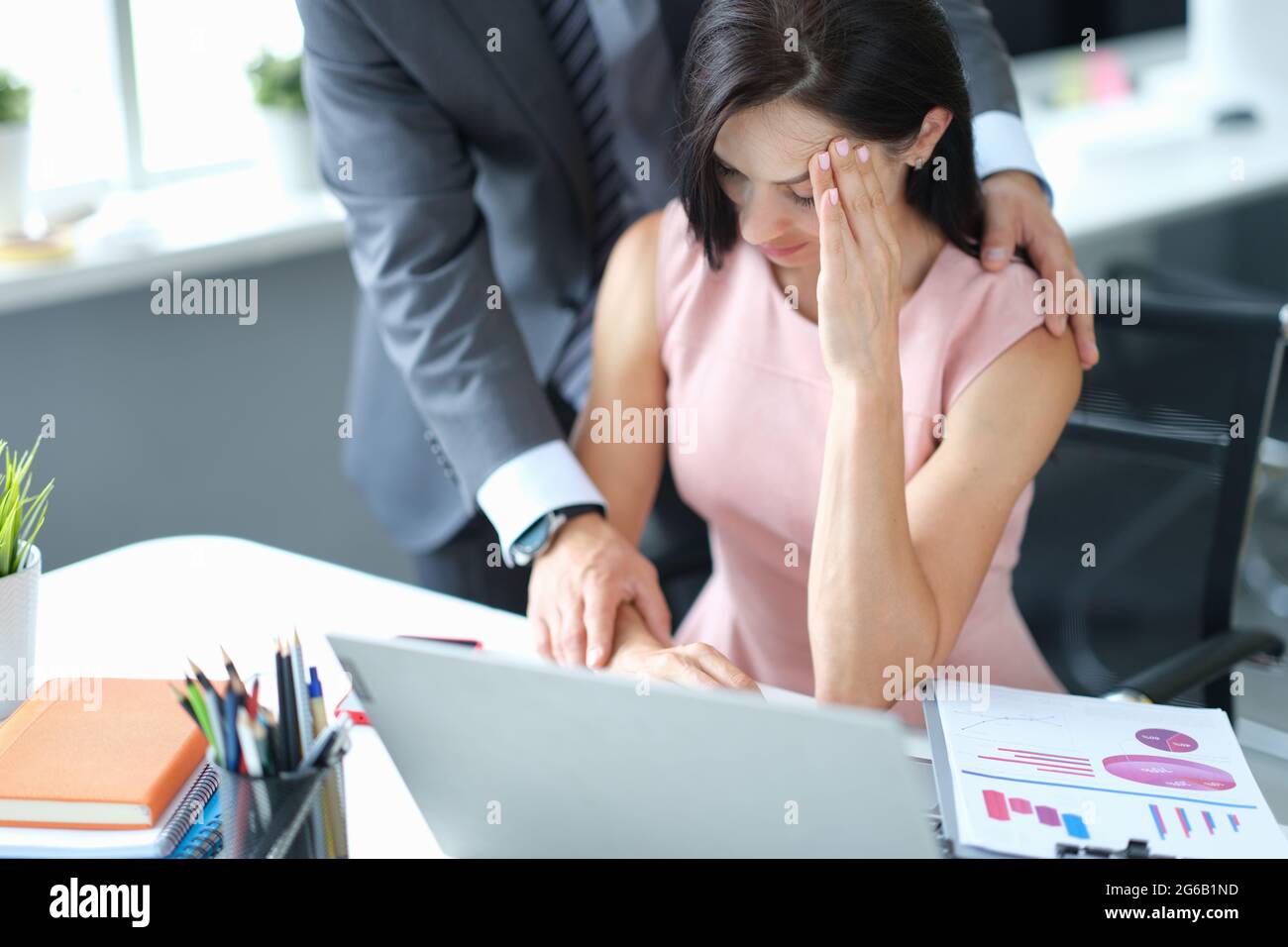 Businessman calming down young fatigue colleague at workplace Stock Photo