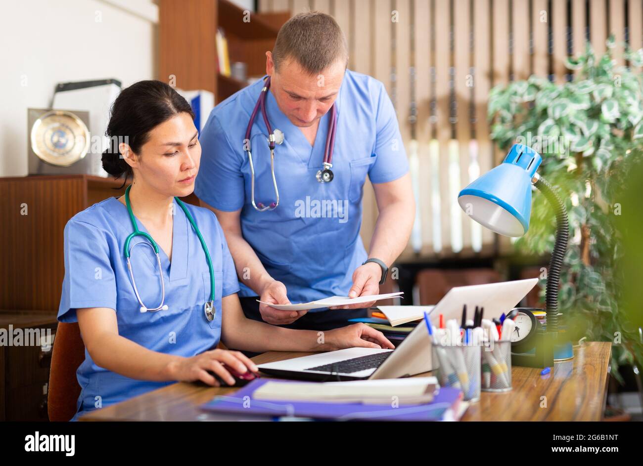 Two focused physicians working with case histories on laptop Stock Photo