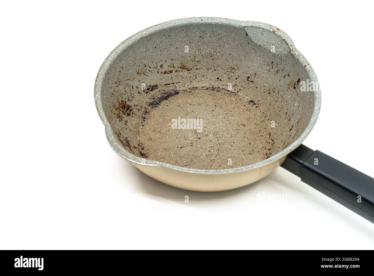 Small modern saucepan with burning mark on the surface, modern pan with black handle, 45-degree angle view, the image on white background. Stock Photo